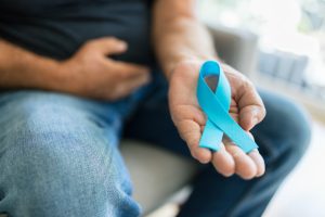 Senior man holding a blue cancer awareness ribbon
