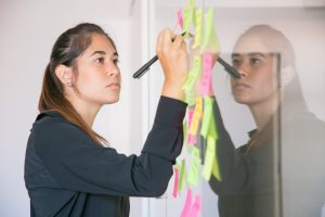 Young Latin businesswoman writing on sticker with marker